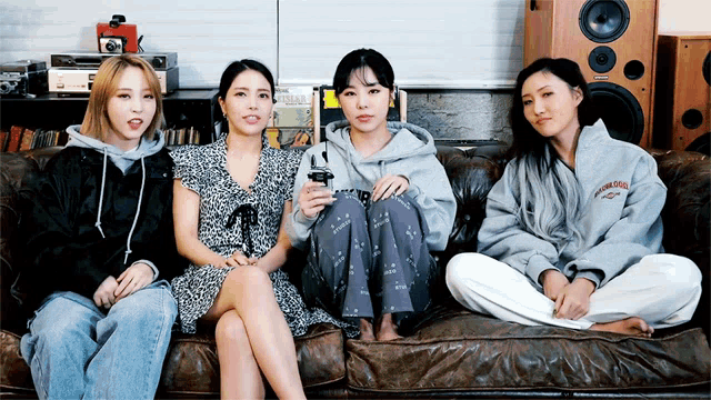 four women are sitting on a couch with one wearing a sweatshirt that says ' california ' on it