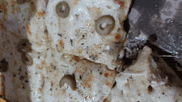 a close up of a pizza with cheese and olives on it