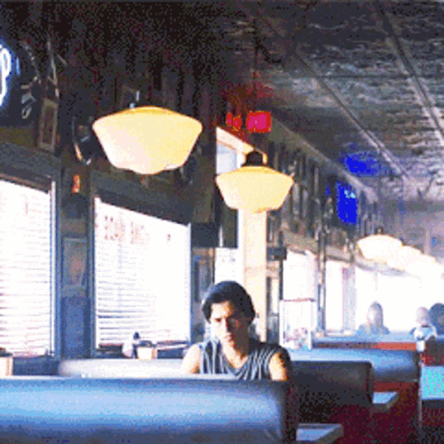 a man sits in a booth in a diner with a sign that says ' a ' on it