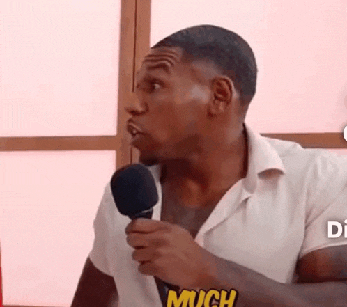 a man in a white shirt is holding a microphone in his hand and talking into it .