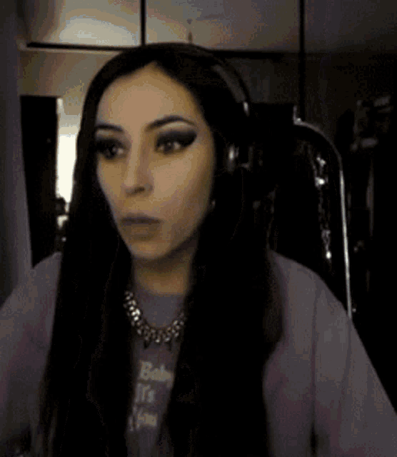 a woman with long hair is wearing headphones and a purple shirt that says baby on it