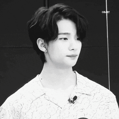 a black and white photo of a young man wearing a microphone and earrings .