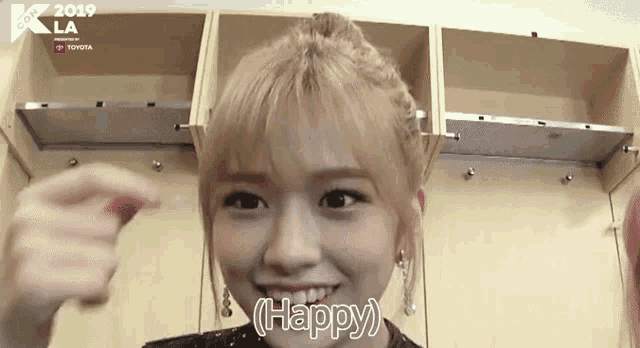 a woman with blonde hair is smiling and saying happy in a locker room .