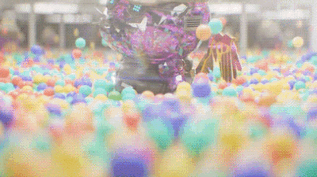 a robot is standing in a ball pit filled with colorful plastic balls