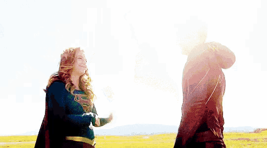 a man and a woman are standing next to each other on top of a hill .