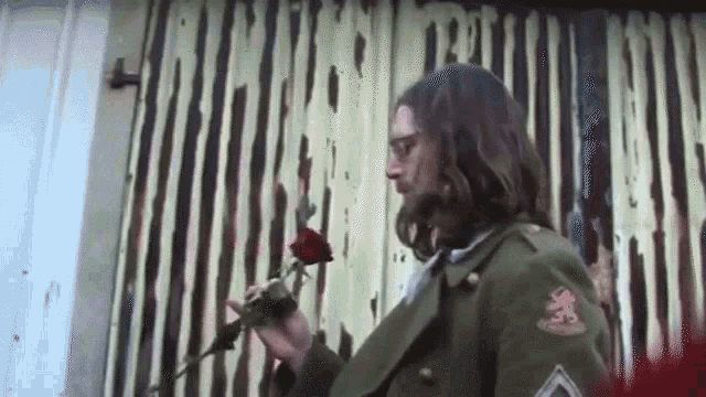 a man in a military uniform is holding a rose