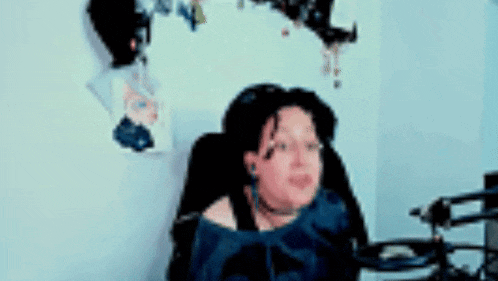 a woman is sitting in a chair wearing headphones and a blue shirt .