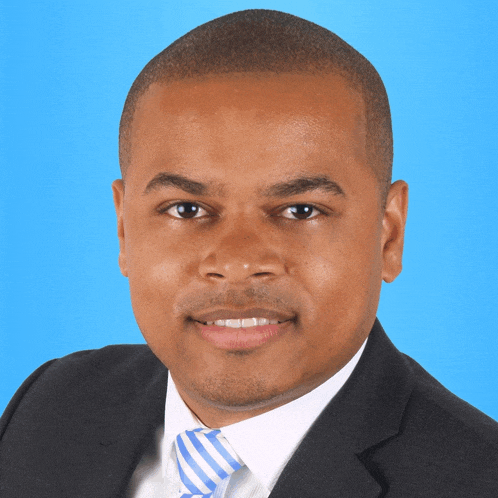 a man wearing a suit and tie against a blue background