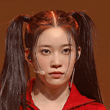 a close up of a woman 's face with pigtails and a red jacket