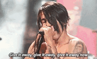 a shirtless man singing into a microphone with the words give it away give it away give it away now written below him .