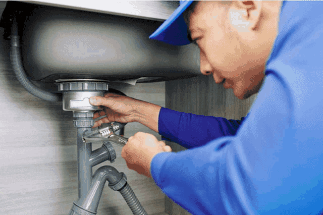 a man in a blue shirt and hat is fixing a sink