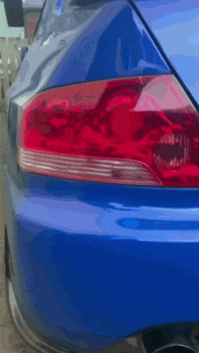 a blue car with a red tail light is parked