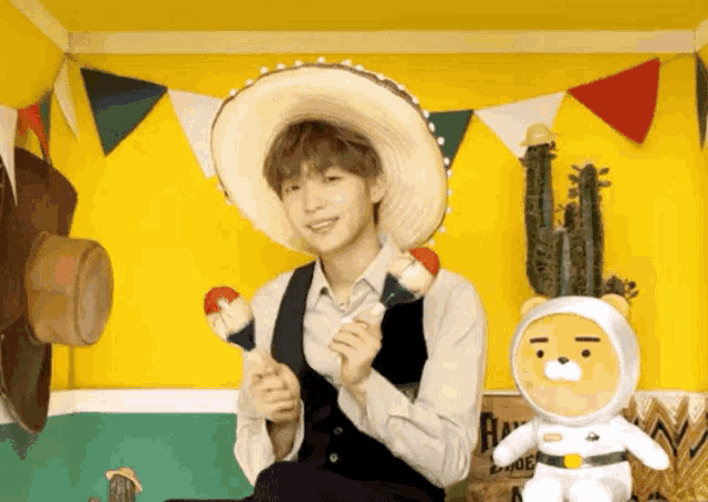 a man wearing a sombrero is holding maracas next to a stuffed bear