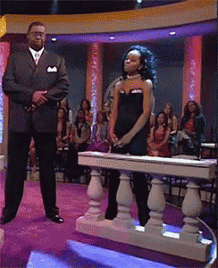 a man in a suit stands next to a woman in a black dress on a stage