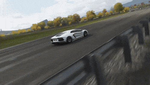 a white sports car is driving down a road with a fence in the foreground