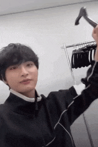 a young man is holding a hanger over his head in a dressing room .