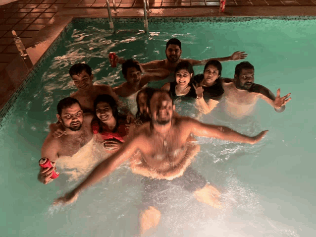 a group of people are swimming in a pool and one of them is holding a coca cola can
