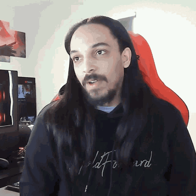 a man with long hair and a beard wears a black shirt that says " flat forward " on it