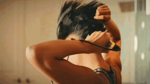 a woman in a bra is holding her hair in a bun .