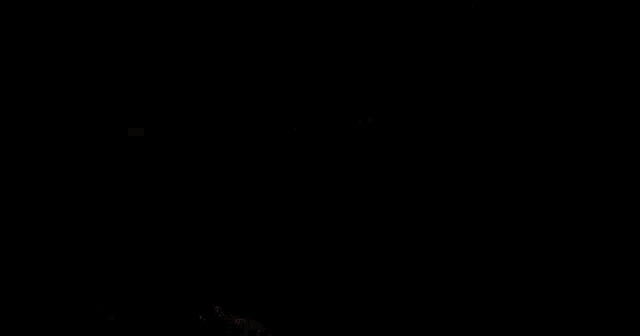a monster with bright eyes is standing in the dark with its mouth open .