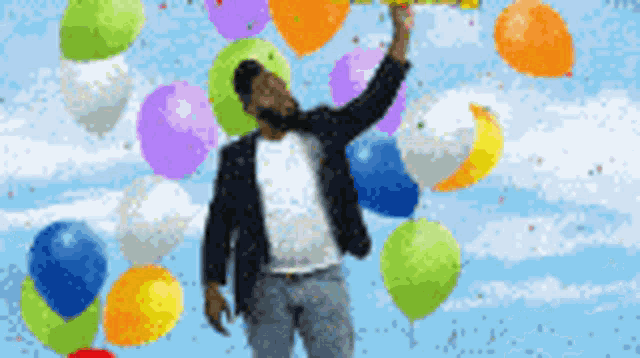 a man is standing in front of a bunch of balloons and holding a sign