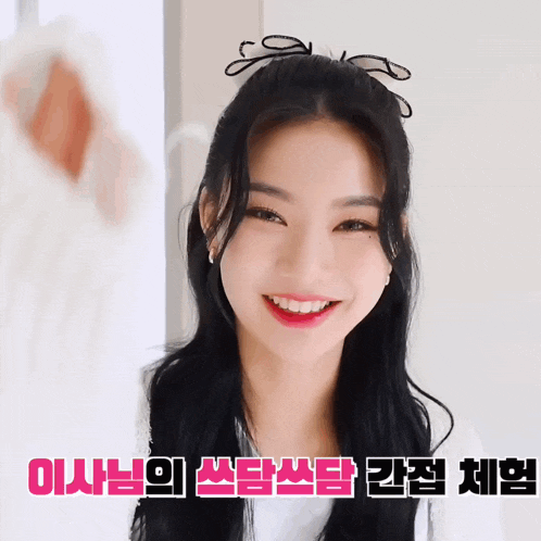 a girl with a bow in her hair is smiling in front of a sign that says oi