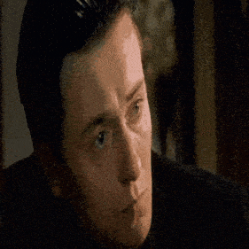 a man in a suit and blue tie is making a funny face .