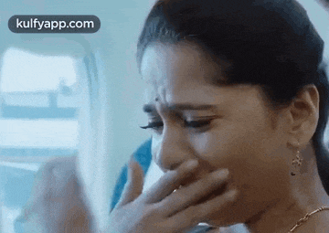 a woman is covering her mouth with her hand while crying on a plane .