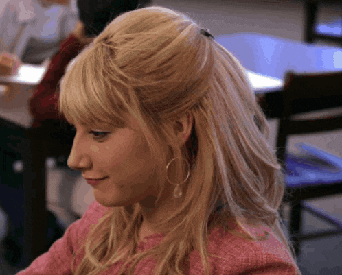 a woman with blonde hair and hoop earrings is sitting at a table