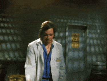 a man in a lab coat is pointing at something in front of a sign that says " caution "