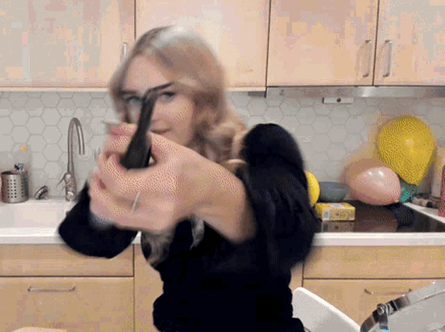 a woman in a black shirt is holding a black object