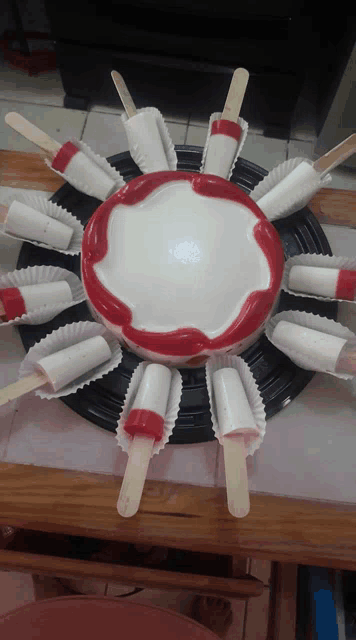a cake with red and white frosting and ice cream on sticks around it