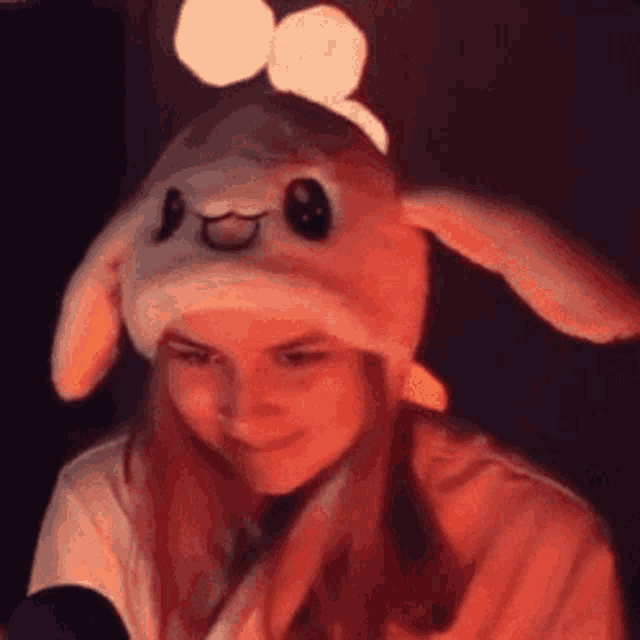 a girl wearing a bunny hat with moving ears is sitting in front of a microphone .