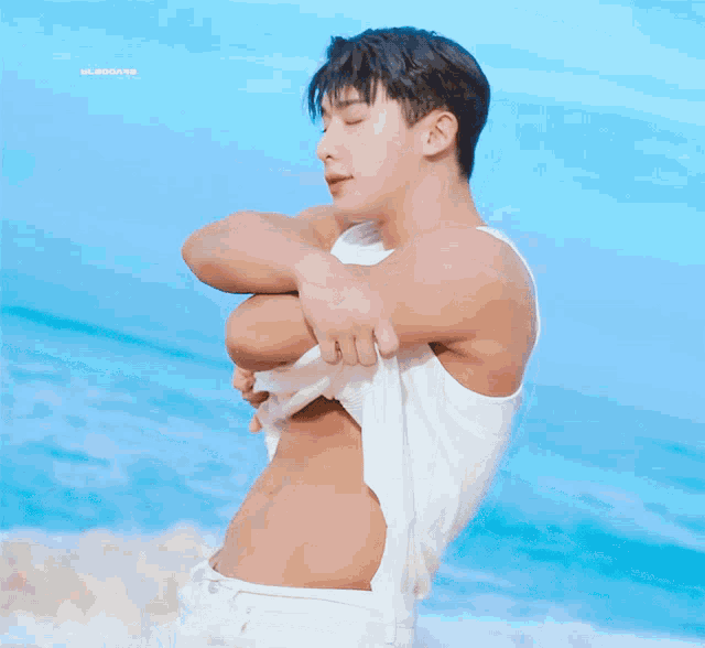 a man without a shirt is standing on a beach with a blue sky behind him and the word blooms on the bottom