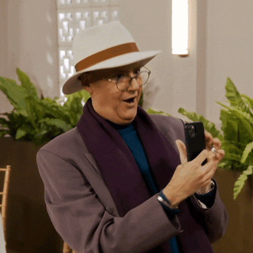 a man wearing a white hat and glasses holds a cell phone