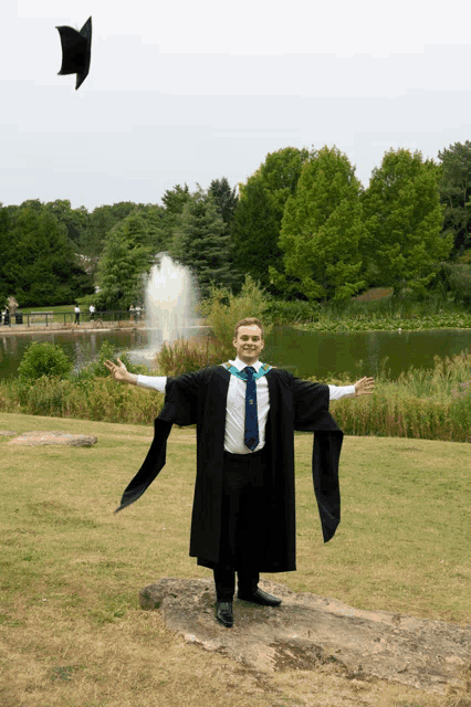 a man in a graduation gown throws his cap in the air