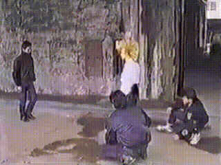 a group of people standing and kneeling on the ground in front of a wall