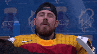 a man with a beard is wearing a yellow shirt and a hat