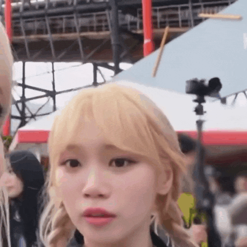 a woman with blonde hair is making a funny face while standing in front of a camera .
