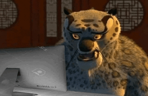 a cartoon leopard is sitting at a table looking at a laptop computer .