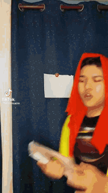 a man wearing a red scarf and a yellow shirt is holding a nintendo wii .