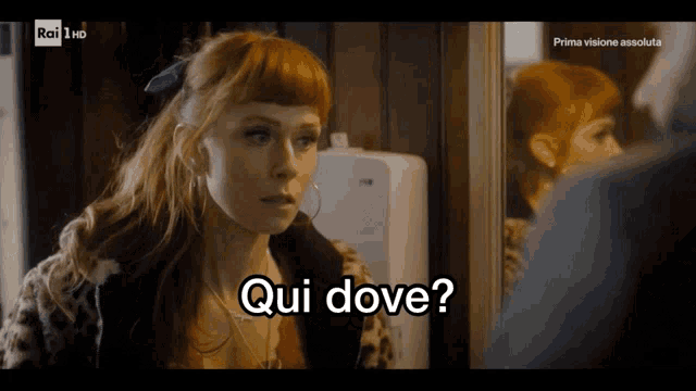 a woman with red hair says " qui dove " while looking at herself in a mirror