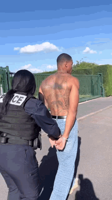 a police officer leads a shirtless man handcuffed