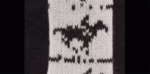 a black and white knitted scarf with a bat pattern