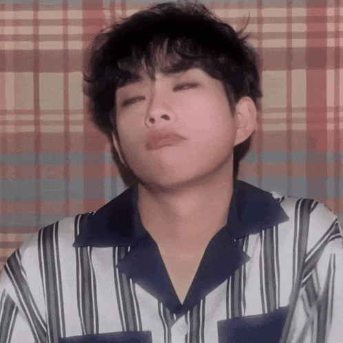 a young man wearing a striped shirt makes a funny face