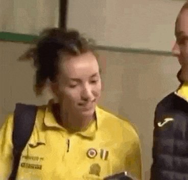 a man and a woman are standing next to each other in a room . the woman is wearing a yellow shirt .