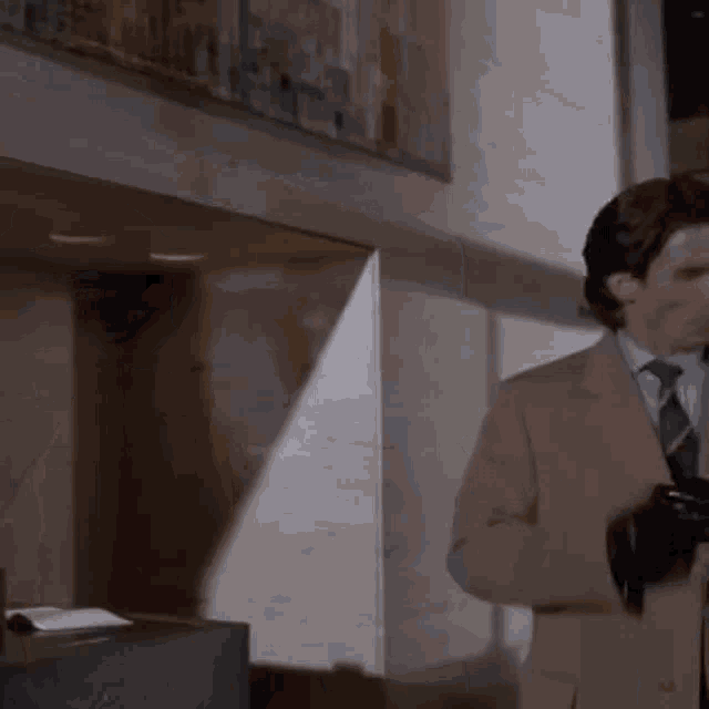 a man in a suit and tie stands in front of a window