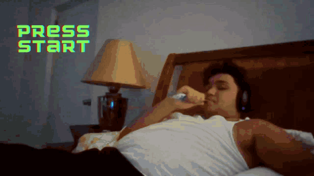 a man laying on a bed with headphones and the words press start behind him