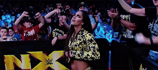 a woman is standing in front of a crowd in front of a sign that says nxt