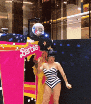 a woman is dancing in front of a barbie display